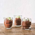 Chocolate avocado coconut mousse in three glasses, each garnished with avocado purée and coconut flakes.