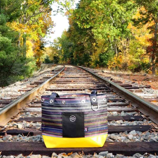 On the Road Again - Raymond Yellow Tote Bag on train tracks.