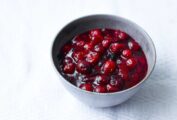 Spicy cranberry sauce in a grey pottery bowl on a white tablecloth.