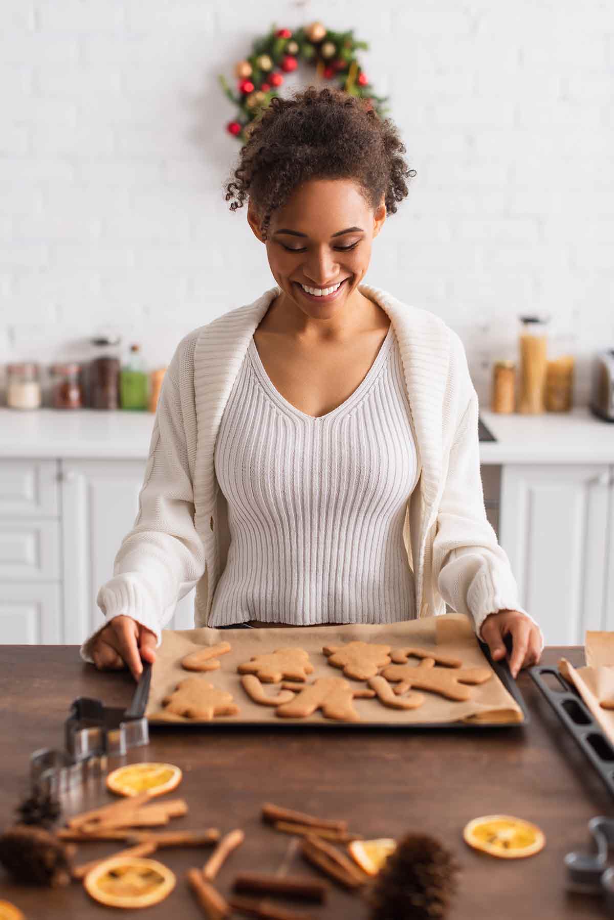 A woman holding a baking tray of gingerbread cookies