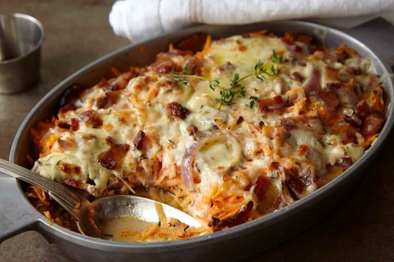 A chicken, sweet potato, and bacon casserole in an oval dish, topped with melted cheese