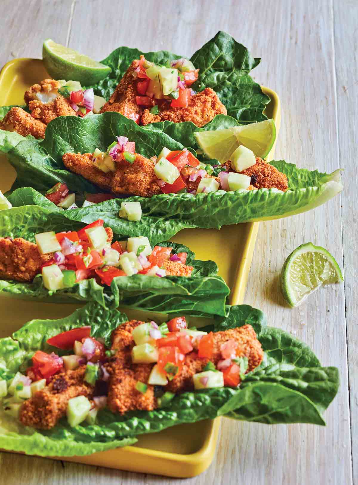 Four low-carb fish tacos--almond-meal coated cod and cucumber salsa in lettuce leaves--with a slice of lime. You're gonna love these babies!