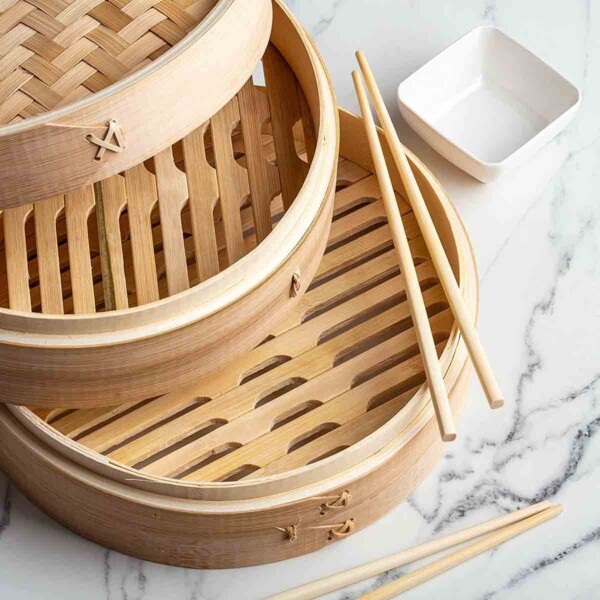 Bamboo Steamer Basket open on marble counter with chopsticks.
