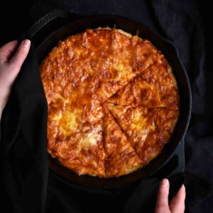 An easy skillet pizza for kids in the pan being held by a woman's hands