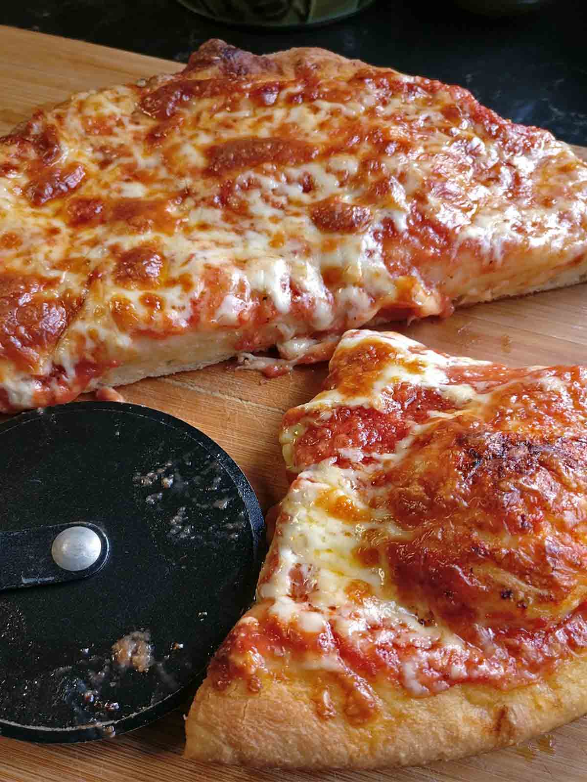 An easy skillet pizza for kids on a cutting board, cut in half, a pizza cutter on the site